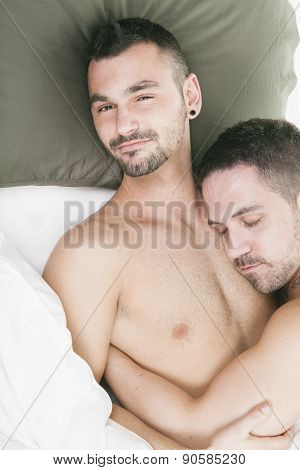 A homosexual couple onder a bed in studio white