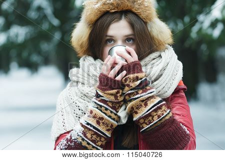 Portrait of girl with hiding her face behind tourist vacuum flask cup with hot drink outdoors