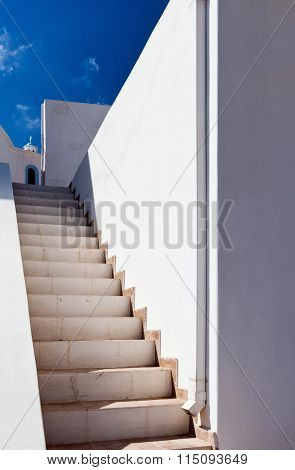 Stairs white walls and a church.