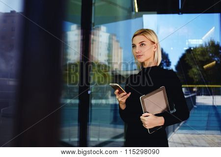 Female lawyer waiting for mobile phone call after use touch pad while standing outside company