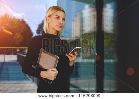 Young skilled businesswoman hold touch pad and cell telephone while waiting for a meet with partner