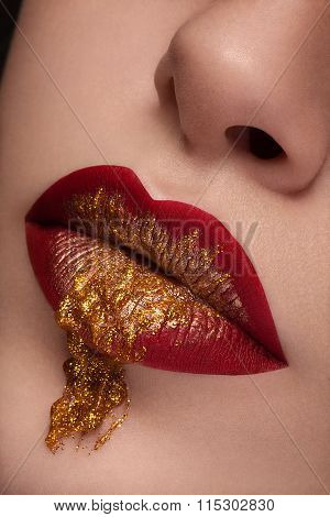 Close Up Red Lips With Gold Liquid Flowing From Lips