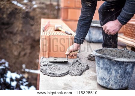 Construction Worker Using Trowel And Cement For Installing The Brickwork