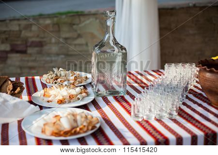 Traditional Ukrainian Wedding Feast Table At Reception: Vodka Bottle, Snacks And Glasses On Embroide