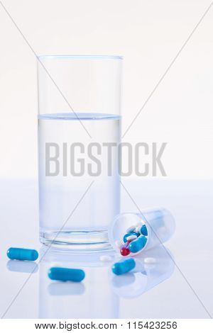 Glassful of water and bunch with pills