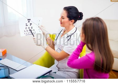 Female pediatrician pointing at eye chart to child