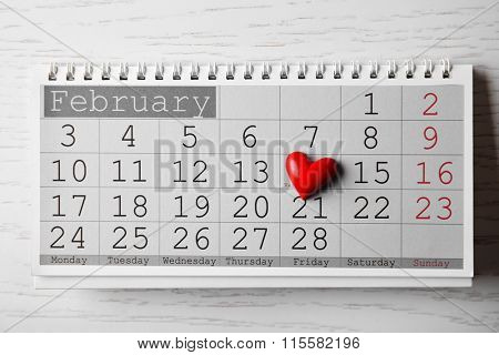 Calendar for Valentines Day with small heart on wooden background