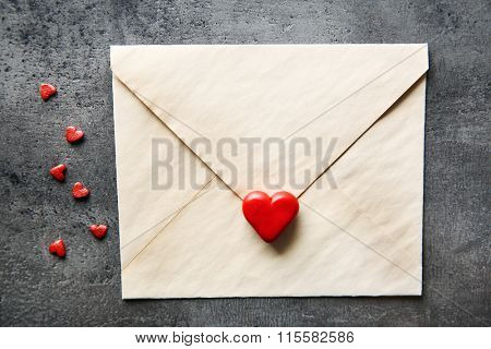 Blank present envelope with small hearts and red rose on grey textured background