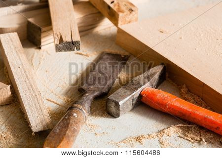 Hammer and chisel  lie on a workbench among scraps of wood