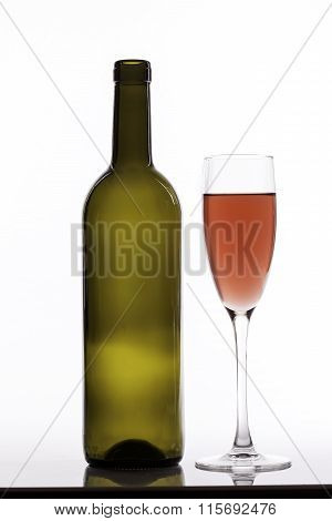 glass of pink wine and empty bottle on white background