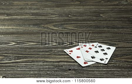 Three Playing Cards Lie On The Wooden Background