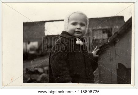 Vintage photo shows a small girl and kannel (doghouse), circa 1942.