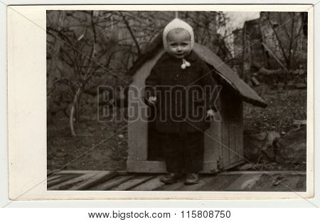 Vintage photo shows a small girl and kannel (doghouse), circa 1942.