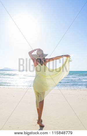Woman walking on the trpical  beach in yellow dress
