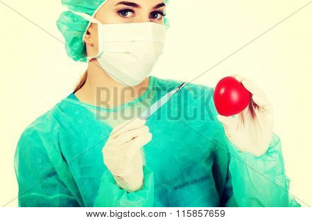 Young female cardiologist surgeron holding heart and scalpel