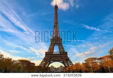 Color fall image of the Eiffel tower in Paris, France, Europe, on a sunny autumn day with blue sky and colorful leaves .