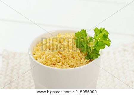 cup of uncooked alphabet pasta on white table mat - close up