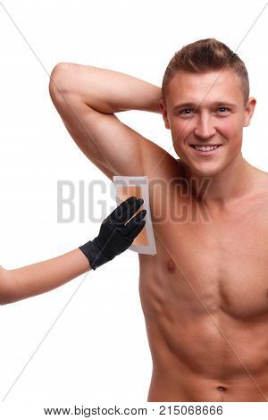 Hand stuck a tape for depilation on an armpit guy with a smile with a bare torso on a white isolated background