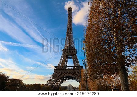 Color fall image of the Eiffel tower in Paris, France, Europe, on a sunny autumn day with blue sky and colorful leaves .