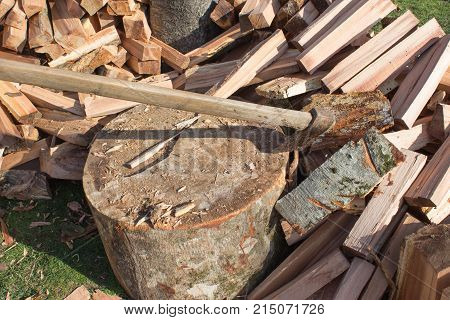 Axe stuck in a stump. Device for chopping trees. Preparing firewood. Chopping wood for fuel. pile of split firewood fuel material