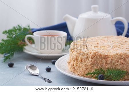Round multi-layered cake Napoleon with custard on a light-blue table background. Selective focus. Toned.