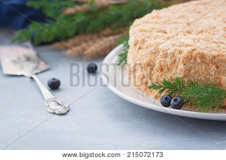Round multi-layered cake Napoleon with custard on a light-blue table background. Selective focus. Toned.