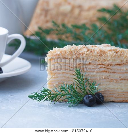 Round multi-layered cake Napoleon with custard on a light-blue table background. Selective focus. Toned.