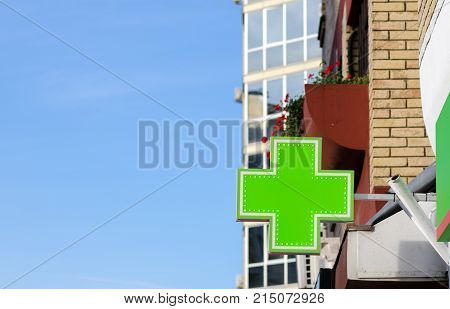 Green cross pharmacy sign or symbol on the building facade view from the street