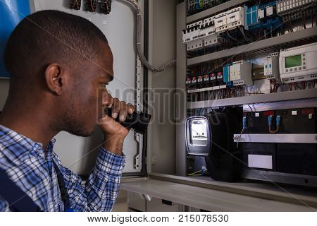 Close-up Of A Electrician Examining A Electric Meter With A Torch