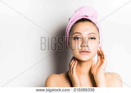 confident beautiful young girl with radiant skin posing with a pink towel on her head