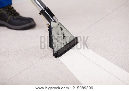 Close-up Of A Person Using Vacuum Cleaner For Cleaning Carpet At Home
