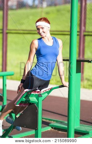 Fitness Ideas and Concepts. Concentrated Caucasian Female Athlete in Professional Outfit Having a Press-Ups Trainig for Belly Muscles. Vertical Image Composition