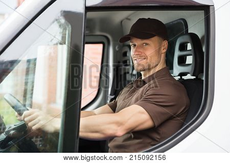 Portrait Of A Happy Young Delivery Man Sitting Inside Van