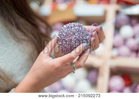 Cheerful happy customer girl choosing Christmas tree decoration balls. difficult decision. Various choice