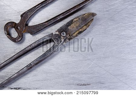 scissors for metal and pincers lay on a sheet of alluminium. vintage.