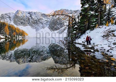 Winter snowshoe hiking by lake at sunrise. Friends hiking by tranquil Blue lake in North Cascades National Park near Winthrop. WA. United States.