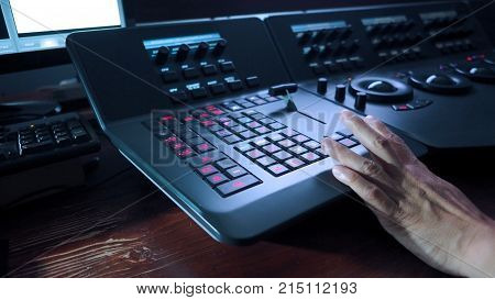 Telecine controller machine and man hand editing or adjusting color on digital video movie or film in the post production stage.