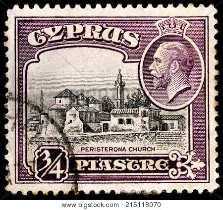 LUGA RUSSIA - OCTOBER 17 2017: A stamp printed by CYPRUS shows image portrait of King George V and view of the Church of St. Barnabas and St. Hilarion Peristerona circa 1934