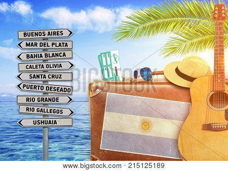 Concept of summer traveling with old suitcase and Argentina town sign with burning sun