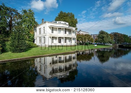 Vicorian White House Reflection On A Calm Canal Water Under A Very Sunny And Blue Sky Day At The Hag