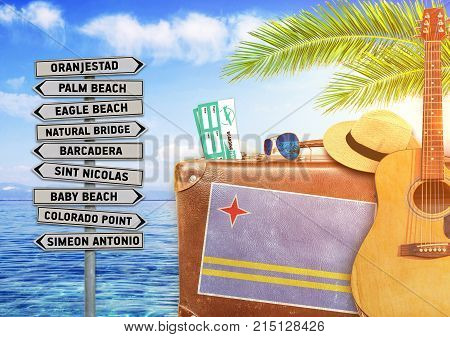 Concept of summer traveling with old suitcase and Aruba town sign with burning sun