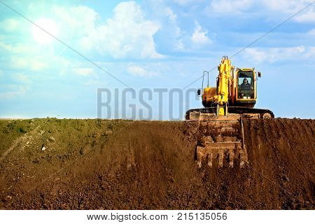 A large construction excavator of yellow color on the construction site in a quarry for quarrying
