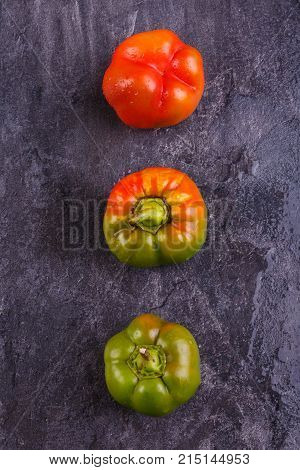 Appetizing, juicy, Bulgarian pepper, decomposed vertically orange and green, mature, and half-ripe, on a black background.