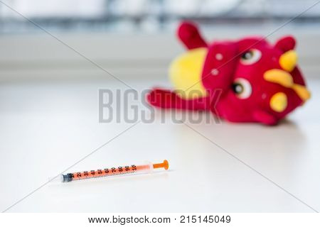 Insulin syringe on child hospital table. Teddy bear in the background.