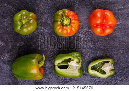 Appetizing, juicy, Bulgarian pepper, cut in half, and whole, orange and green, on a black background