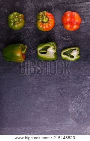 Appetizing, juicy, Bulgarian pepper, cut in half, and whole, orange and green, on a black background. Top view, free space for text.