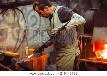 Blacksmith working on metal on anvil at forge high speed detail shot
