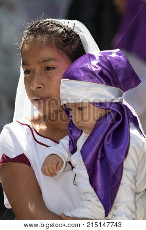 March 6, 2016, San Miguel de Allende, Mexico: young woman holding a young child in her arms both dressed in traditional clothing during Easter procession