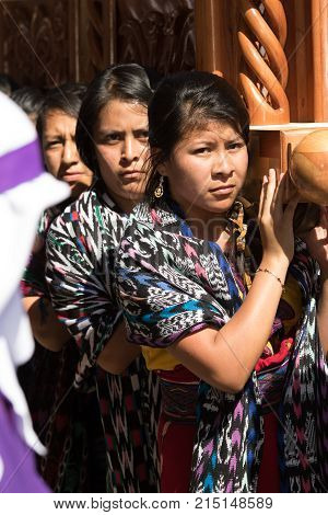 March 25, 2016 San Pedro la Laguna, Guatemala: mayan tzutujil women carrying a heavy float on the street of the small town during Easter holidays
