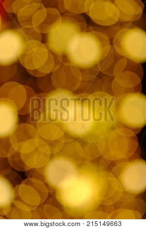 Blurred warm lights of a christmas tree with dark night background,yellow bulbs and colorful bokeh